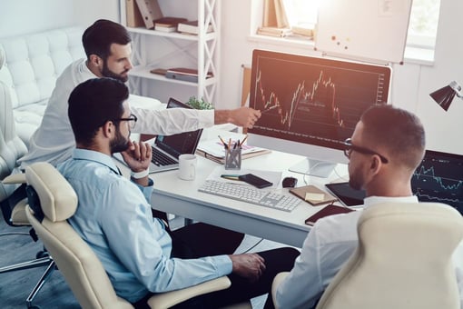 Three coworkers looking at a desktop screen with line graphs